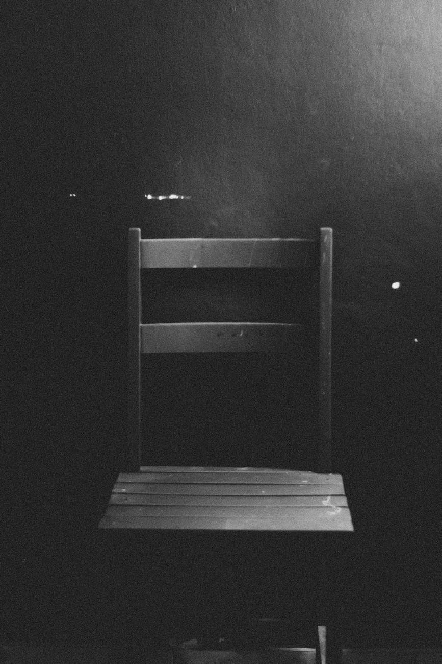 black and white image of an empty chair set against a wall